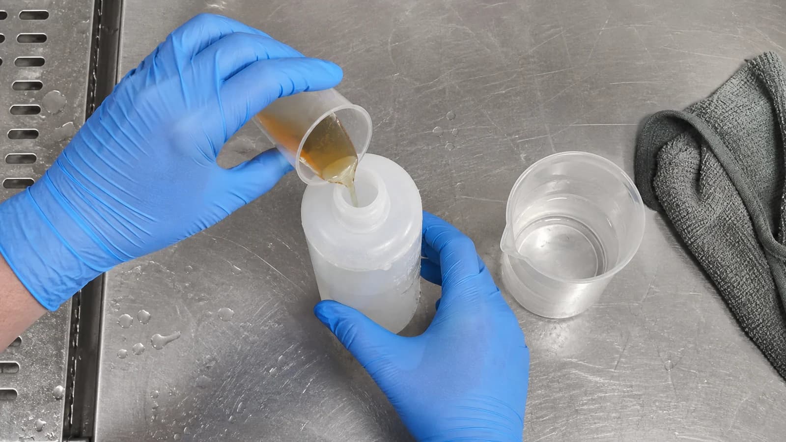 Dog shampoo being measured into an unbranded dilution bottle at a groomer workstation