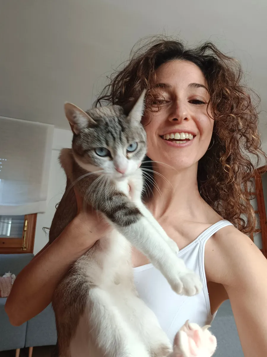 A smiling pet parent holding a gray and white tabby cat