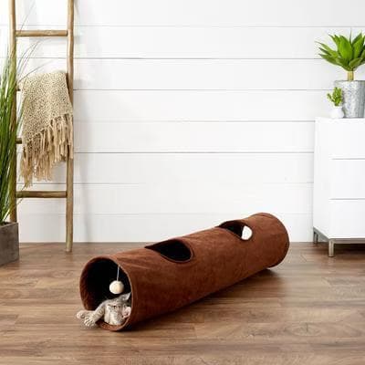 Brown Frisco 47-inch foldable crinkle cat play tunnel with two windows and a dangling ball toy on a wood floor