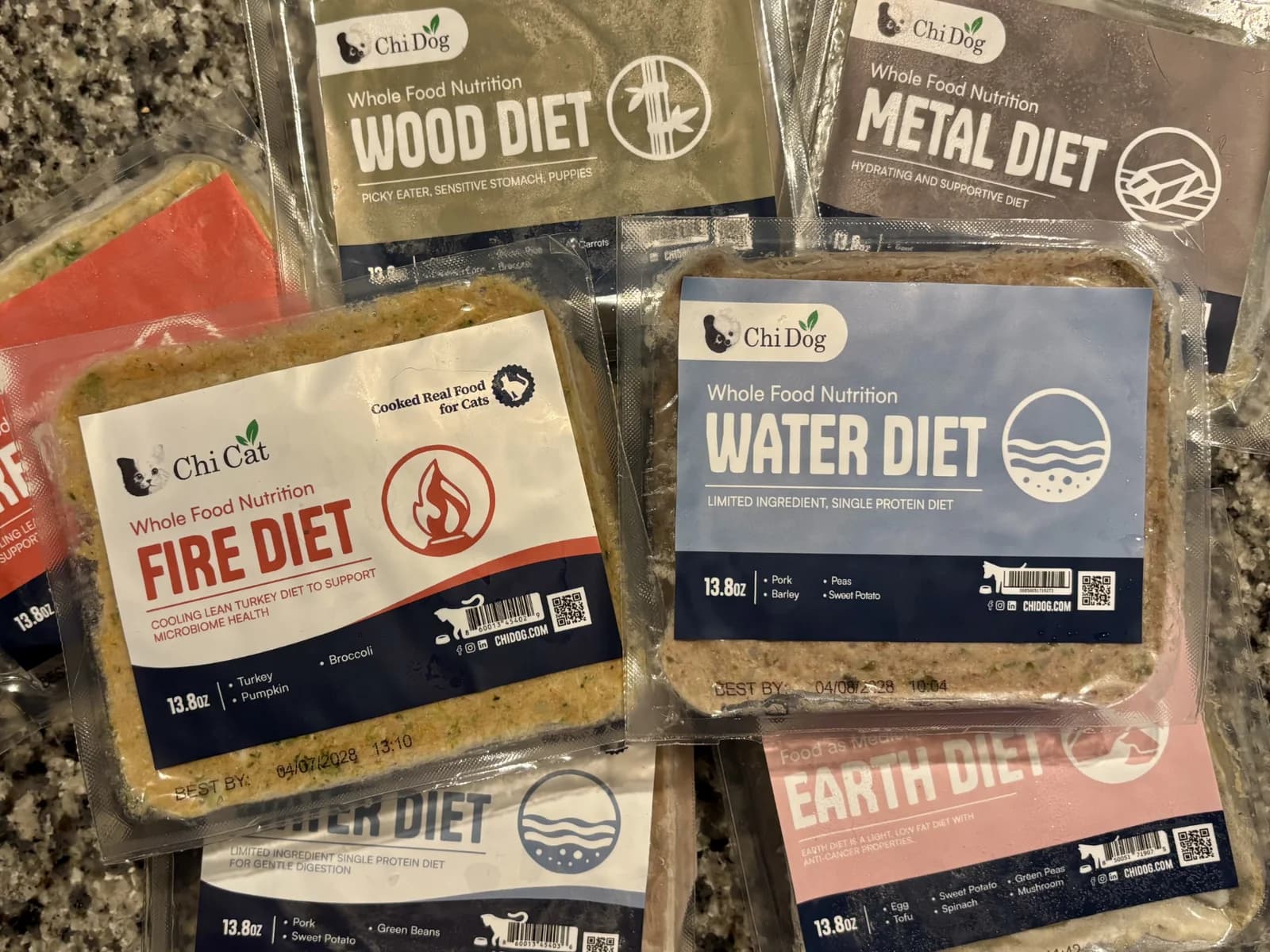 A variety of packaged Chi Dog and Chi Cat food formulas including Fire, Earth, Metal, Water, and Wood diets.