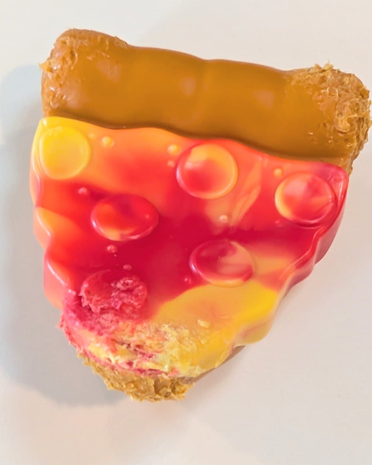 BARK pizza slice dog toy with molded crust and raised sauce bubbles on a white counter