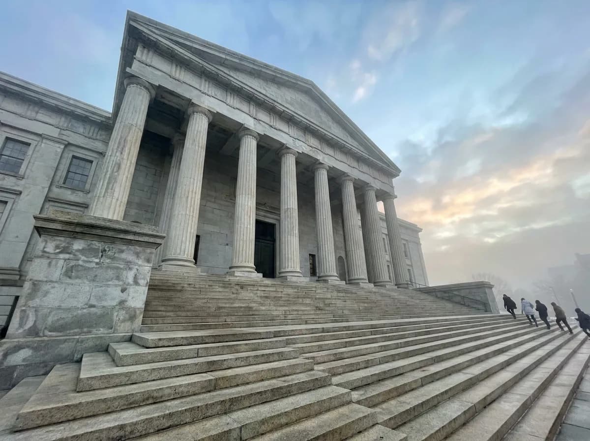 A stone courthouse with tall columns and wide steps under a misty morning sky.