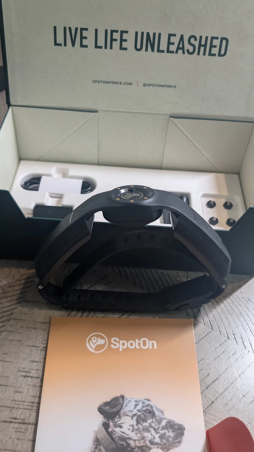 The rigid, curved band of the SpotOn dog collar standing upright in front of the box.