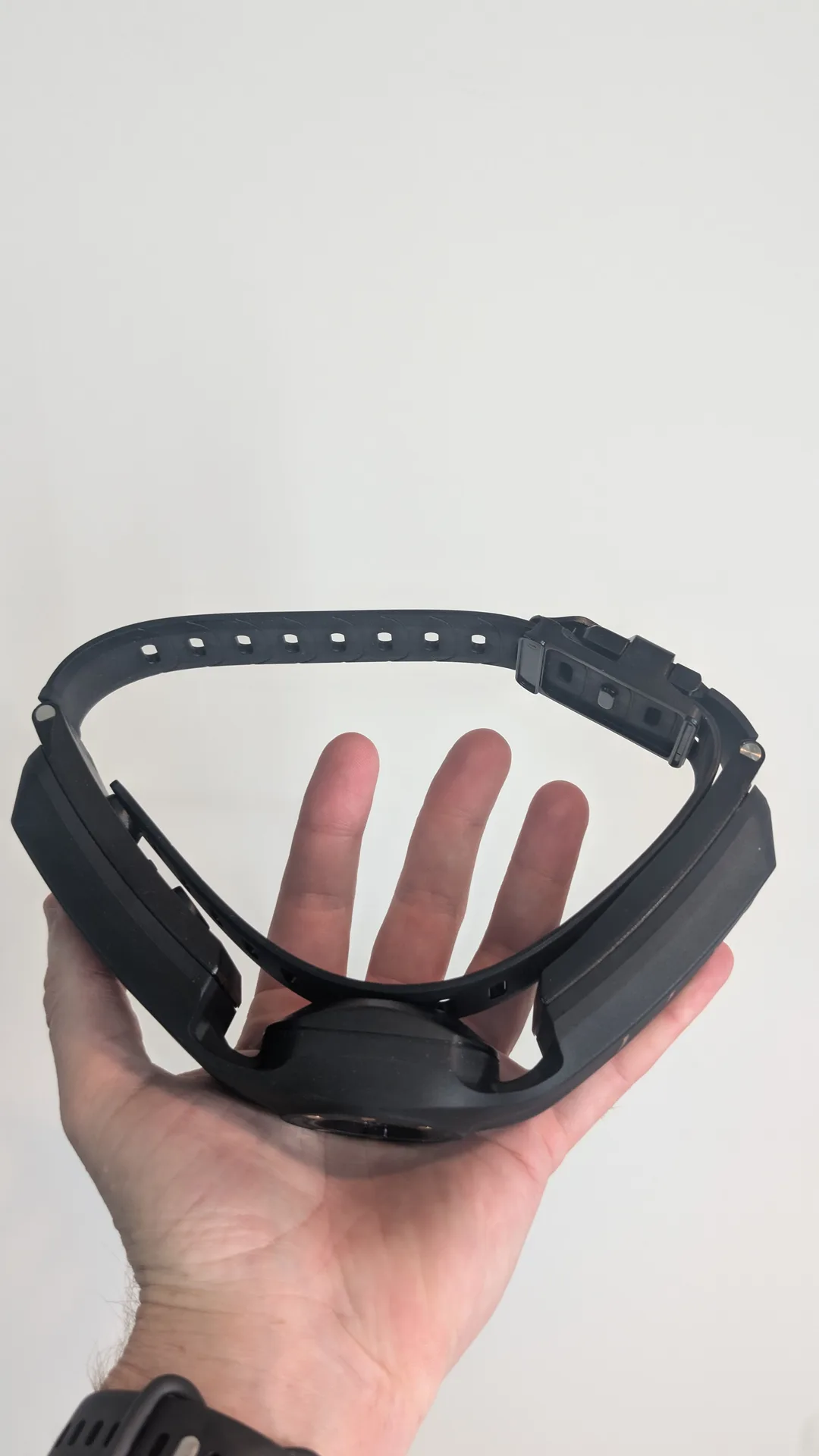 The SpotOn collar strap with adjustment holes and buckle, held in a hand for scale.