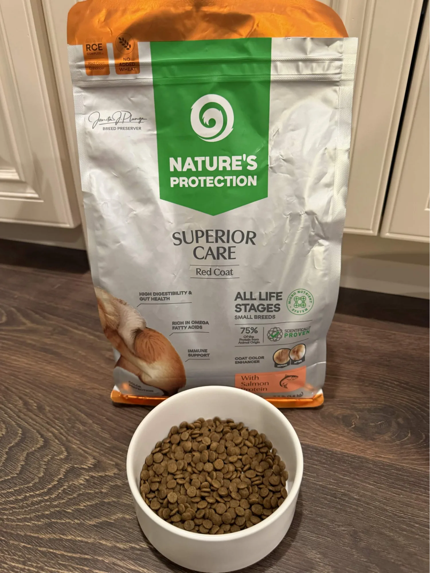 A bowl of small, dark Nature's Protection Red Coat kibble in front of the 3.3-pound bag