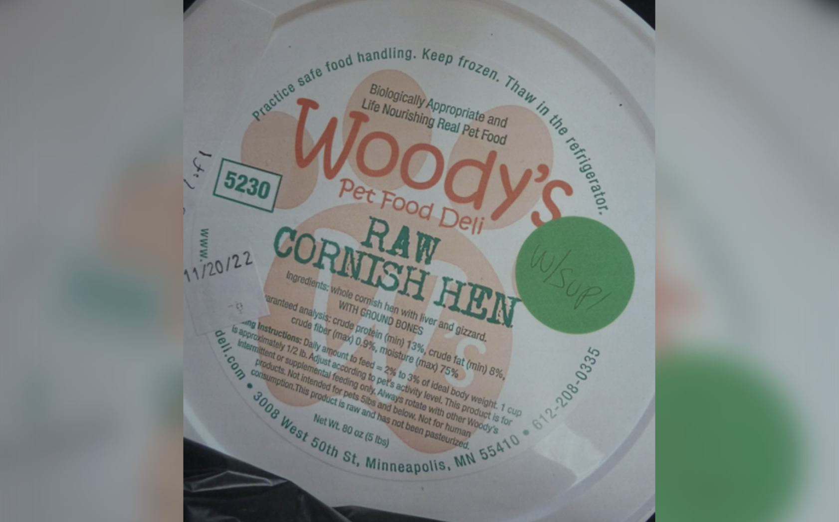 Photo showing the top of the container for Woody's Pet Food Deli Raw Cornish Hen With Supplements -- There is a green sticker with "w/ Suppl" written on it and a white sticker with the expiration date 11/20/22.