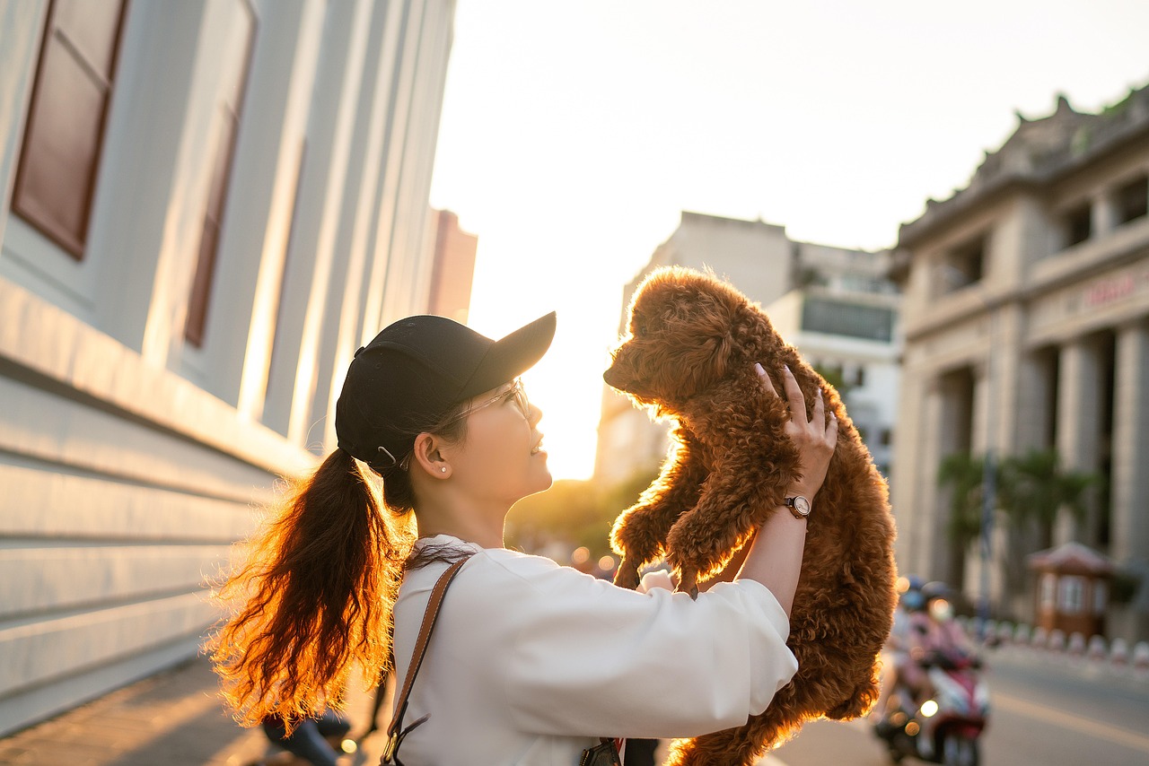 Young woman holding a small dog smiling while shopping for pet supplies with a Nibbles Pet Rewards Credit Card.