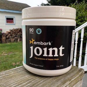 Embark Joint Supplements container sitting on a porch rail, perfect for supporting your dog’s joint health.